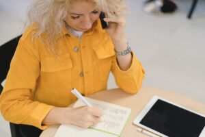 La thérapeute appelle son/sa cliente et prend des notes concernant la séance de kinésiologie ou d'hypnose